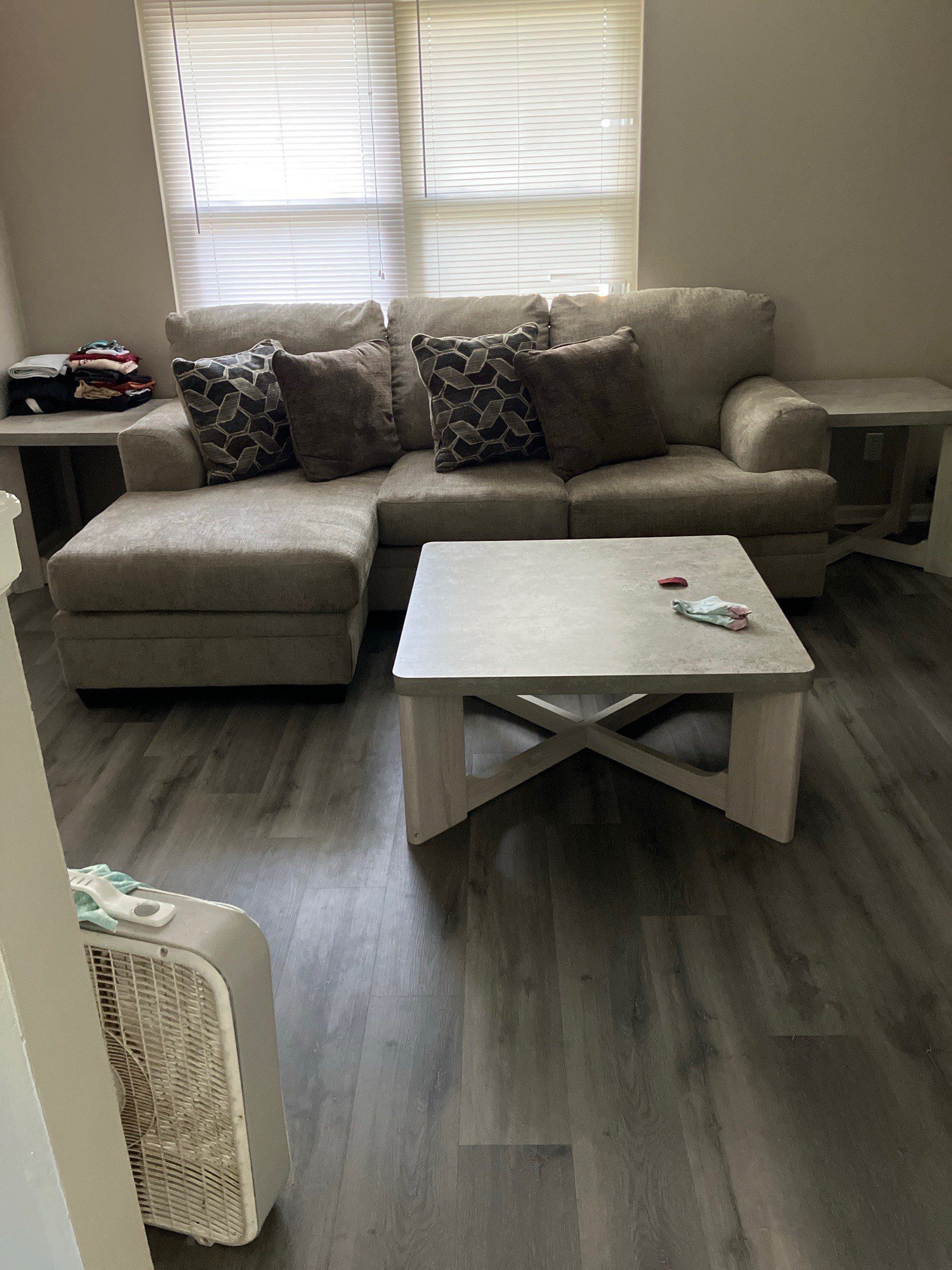 Photo shows a tan L-shaped couch with four throw pillows, and a small coffee table.